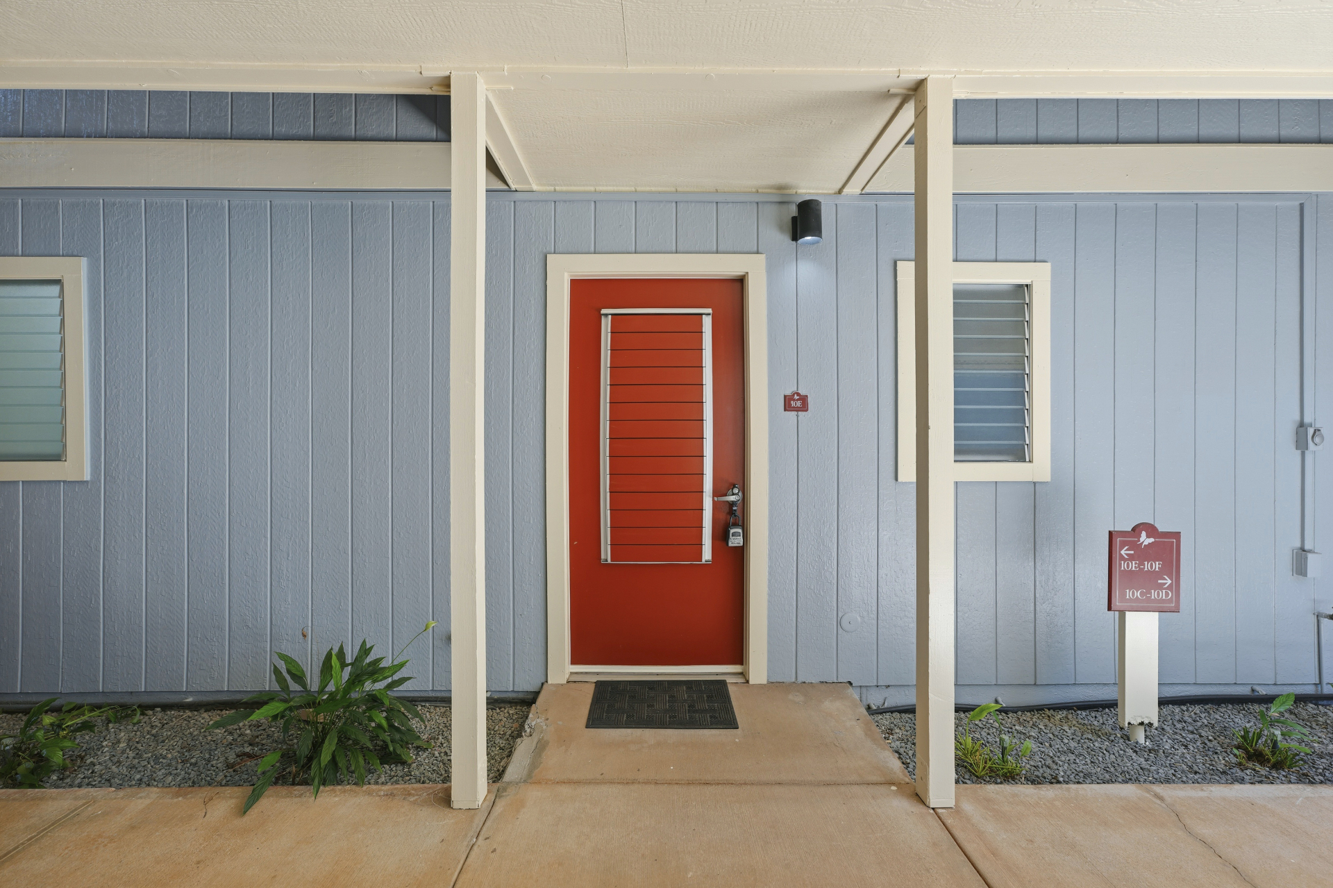 Covered entry with red front door and unit sign
